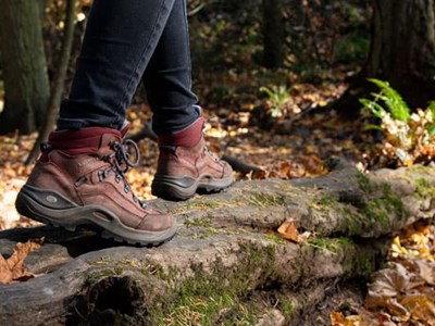 Closeup photo of hiking boots walking across a log.