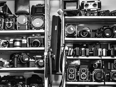 Photo of vintage cameras stacked on a shelf. 