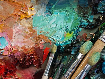Closeup photo of paintbrushes on a  colourful canvas. 