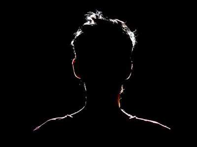 Photo of man in shadow with silhouette outlined by light. 