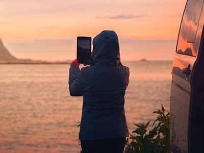 Photo of woman taking picture by water's edge